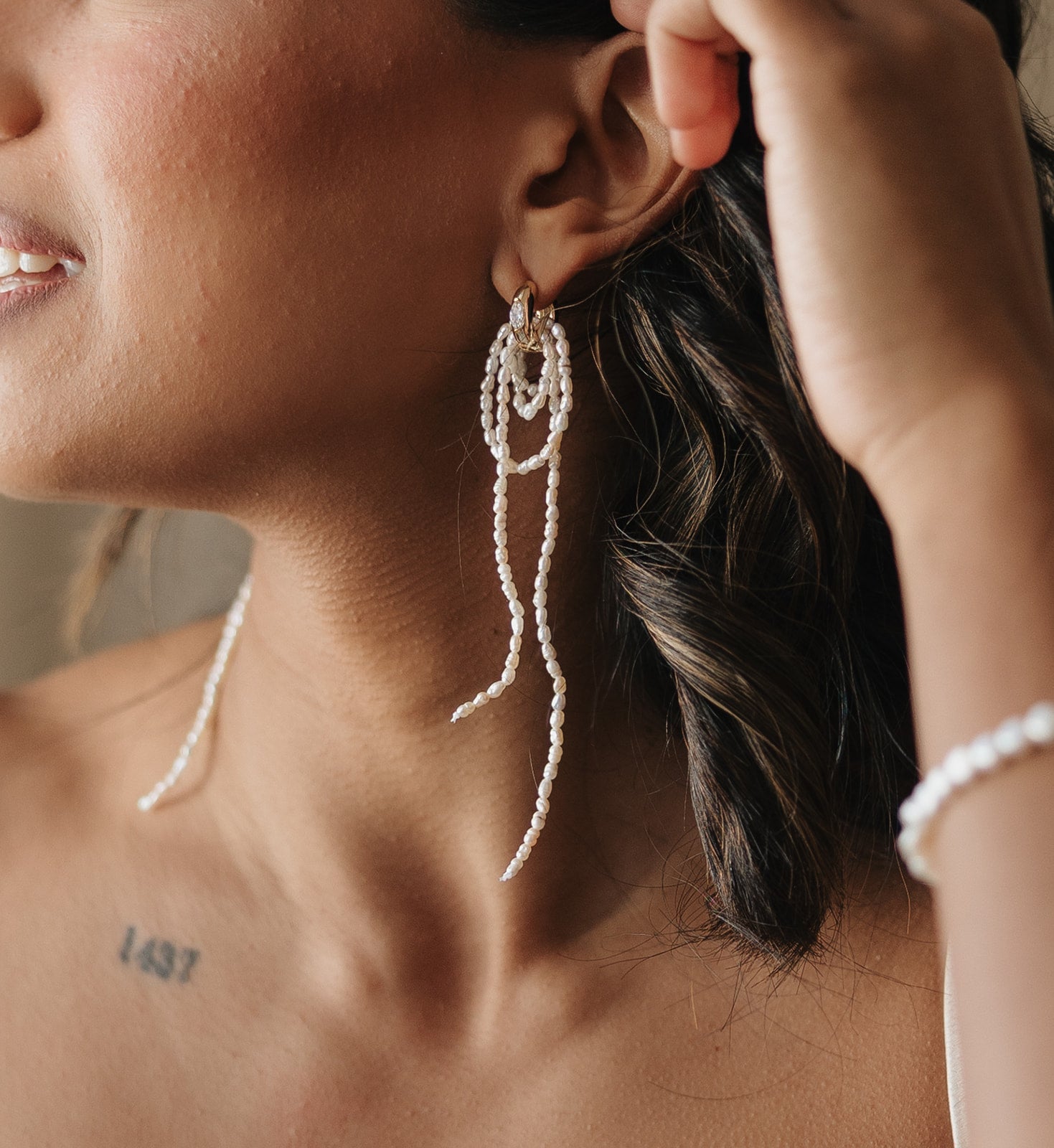 Close-up of a person wearing pearl drop earrings with a blurred background for brides and wedding guests. 