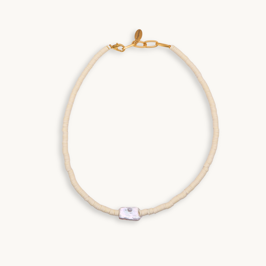 A soft and light yellow bead necklace featuring a single, irregularly-shaped gray pearl at the front. Gold clasp and chain links add a touch of elegance.