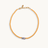 A vibrant orange bead necklace featuring a single, irregularly-shaped gray pearl at the front. Gold clasp and chain links add a touch of elegance.