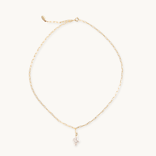 Gold necklace with a small pearl cross pendant on a white background