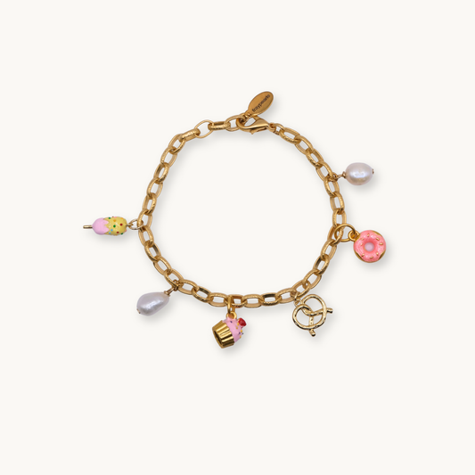 A gold chain bracelet adorned with playful charms: a pink donut, ice cream, cupcake, pretzel, and pearls, evoking a whimsical, cheerful tone.