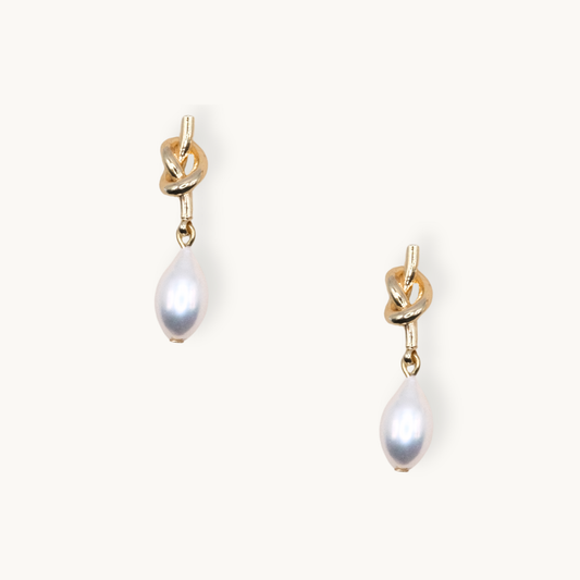 Elegant gold earrings feature a knotted design with teardrop-shaped white pearls, exuding a sophisticated and timeless charm.