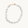 A baroque pearl necklace with irregular white pearls strung along a delicate yellow string. The lustrous pearls convey an elegant, natural look.