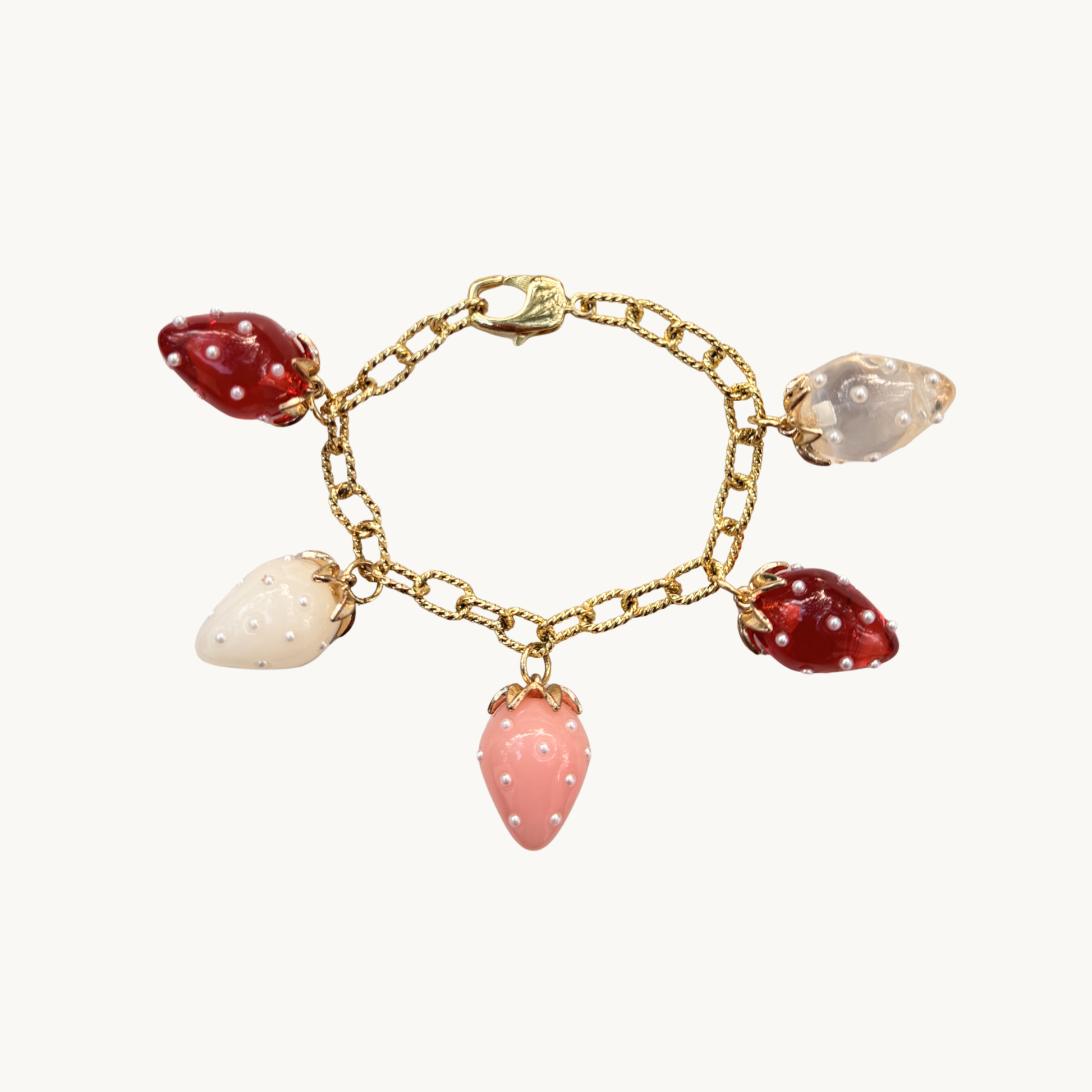 Gold bracelet with strawberry charms in red, pink, white, and clear. Each charm is adorned with tiny pearls, creating a playful, whimsical feel.