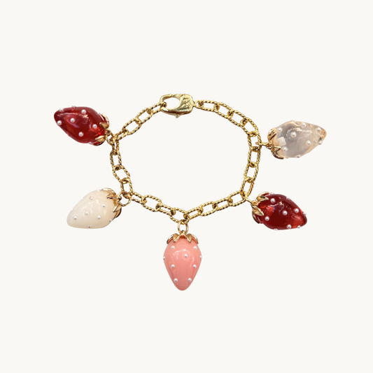 Gold bracelet with strawberry charms in red, pink, white, and clear. Each charm is adorned with tiny pearls, creating a playful, whimsical feel.