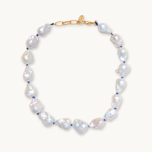 A baroque pearl necklace with irregular white pearls strung along a delicate blue string. The lustrous pearls convey an elegant, natural look.
