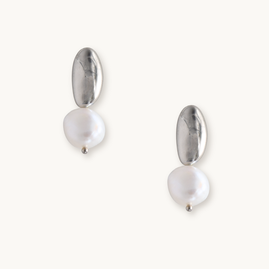 Silver and pearl drop earrings on a white background. Each earring features an irregular gold piece above a baroque pearl, giving an elegant, modern look.
