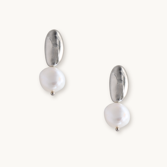 Silver and pearl drop earrings on a white background. Each earring features an irregular gold piece above a baroque pearl, giving an elegant, modern look.