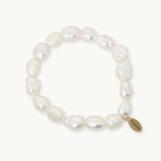 A baroque pearl beaded bracelet with a small gold-tone oval charm engraved with the brand name 'Pierrefini', displayed on a clean off-white background.