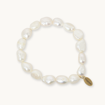 A baroque pearl beaded bracelet with a small gold-tone oval charm engraved with the brand name 'Pierrefini', displayed on a clean off-white background.