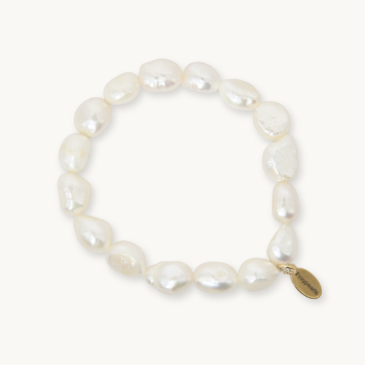 A baroque pearl beaded bracelet with a small gold-tone oval charm engraved with the brand name 'Pierrefini', displayed on a clean off-white background.