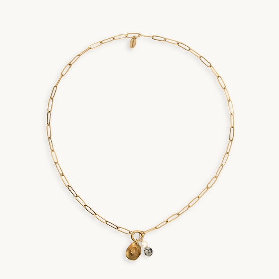 A delicate gold paperclip chain necklace with two small hanging charms, one gold-toned and one jasper and pear, displayed on a clean off-white background.