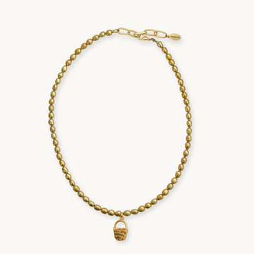 A gold beaded necklace with a small woven basket charm, displayed on a clean off-white background.