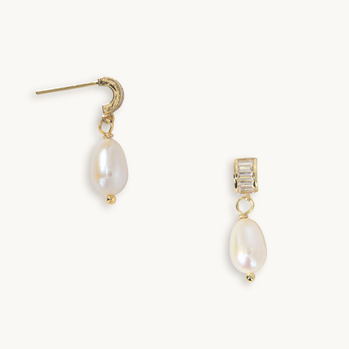 A pair of gold drop earrings featuring a textured gold crescent-shaped stud on one earring and a gold rectangular stud with clear baguette-cut crystals on the other, both hanging from gold posts with teardrop-shaped white freshwater pearls below.