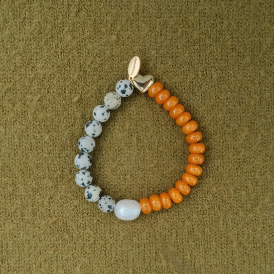 Bracelet half dalmatian-spotted stones and half bright orange rondelles, joined by a freshwater pearl and a golden puffed heart with a Fraypearls tag.