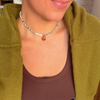 Woman in an olive cardigan wearing a dalmatian-spotted choker with a few freshwater pearls and a tiny red ladybug charm.