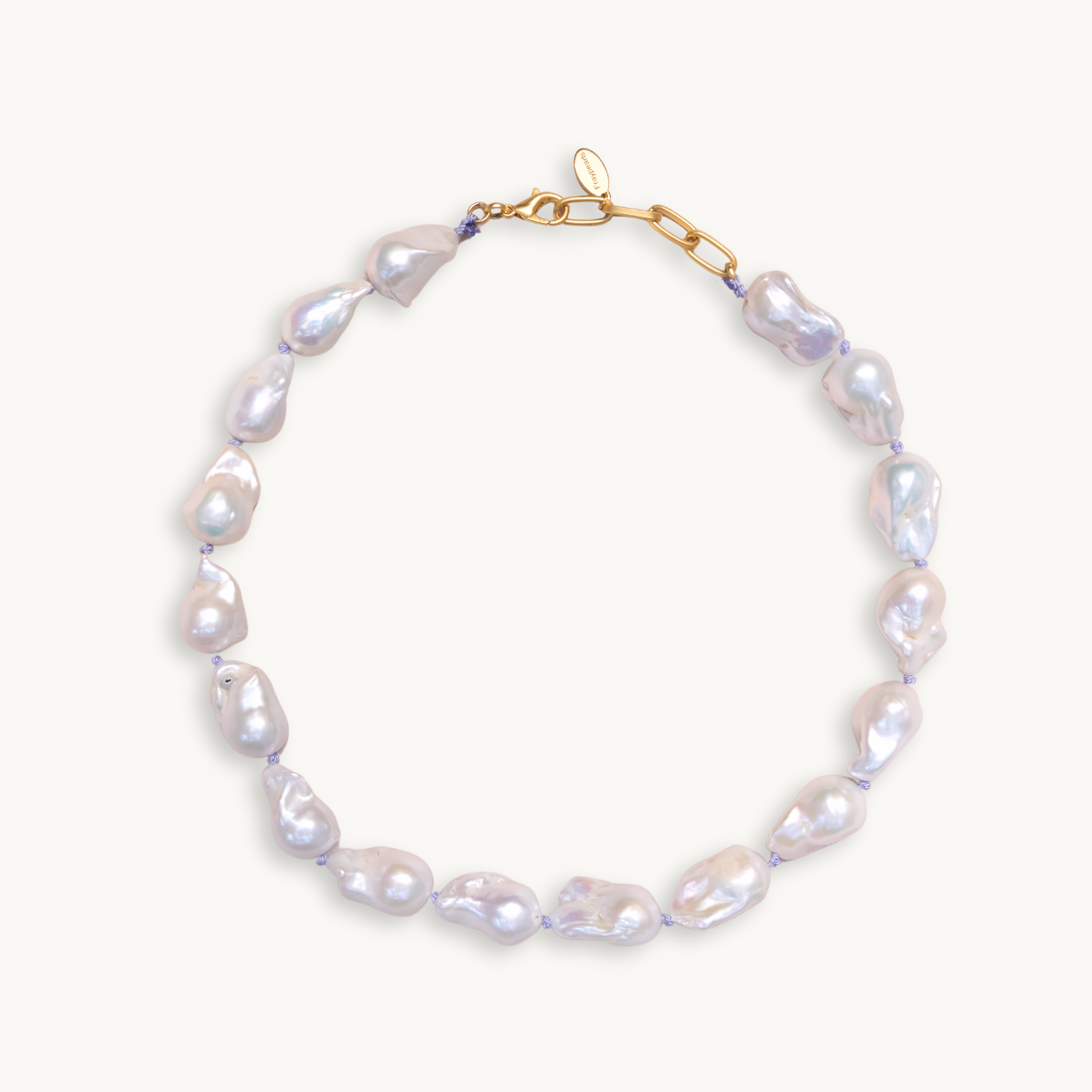 A baroque pearl necklace with irregular white pearls strung along a delicate lilac string. The lustrous pearls convey an elegant, natural look.