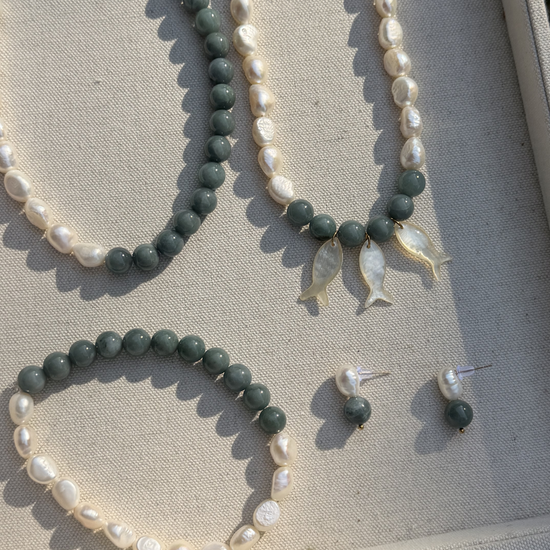Set of jade and pearl jewelry including two necklaces, an  anklet, and earrings on a jewelry tray.
