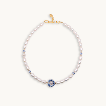 Elegant necklace featuring white pearls with blue floral ceramic bead accents and a gold clasp. The design conveys a sense of classic sophistication.