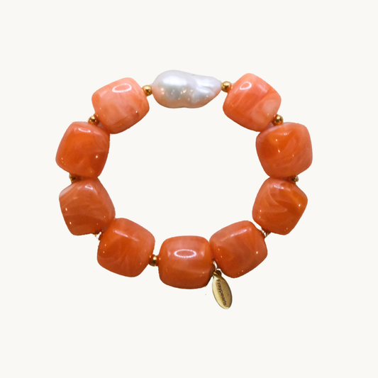 Bracelet with orange beads and a central pearl on a white background