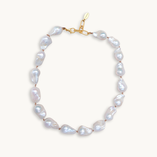 A baroque pearl necklace with irregular white pearls strung along a delicate golden string. The lustrous pearls convey an elegant, natural look.
