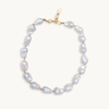 A baroque pearl necklace with irregular white pearls strung along a delicate golden string. The lustrous pearls convey an elegant, natural look.