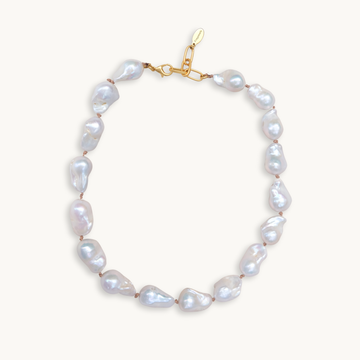 A baroque pearl necklace with irregular white pearls strung along a delicate golden string. The lustrous pearls convey an elegant, natural look.