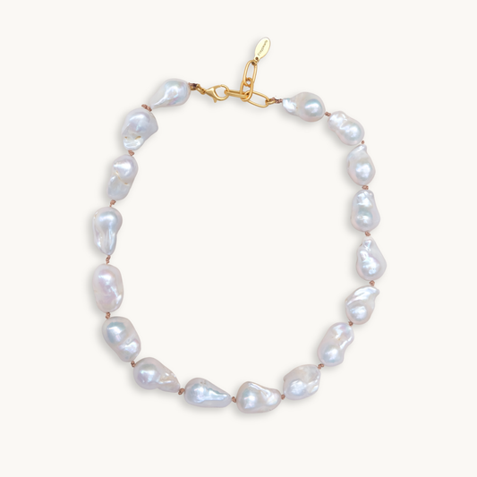 A baroque pearl necklace with irregular white pearls strung along a delicate golden string. The lustrous pearls convey an elegant, natural look.