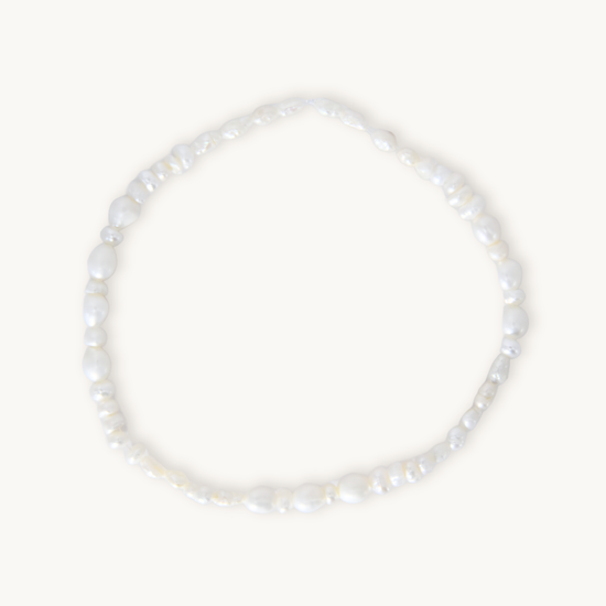 A barely-there pearl bracelet featuring organically shaped white pearls on a comfortable elastic band, designed for effortless, everyday wear. Lightweight and flexible, it slips on with ease, making it perfect under scrubs or as the finishing touch to your most polished look.