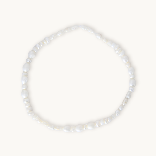 A barely-there pearl bracelet featuring organically shaped white pearls on a comfortable elastic band, designed for effortless, everyday wear. Lightweight and flexible, it slips on with ease, making it perfect under scrubs or as the finishing touch to your most polished look.