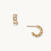 Gold hoop earrings with a textured finish and delicate pearl accents, designed to add dimension and effortless elegance.