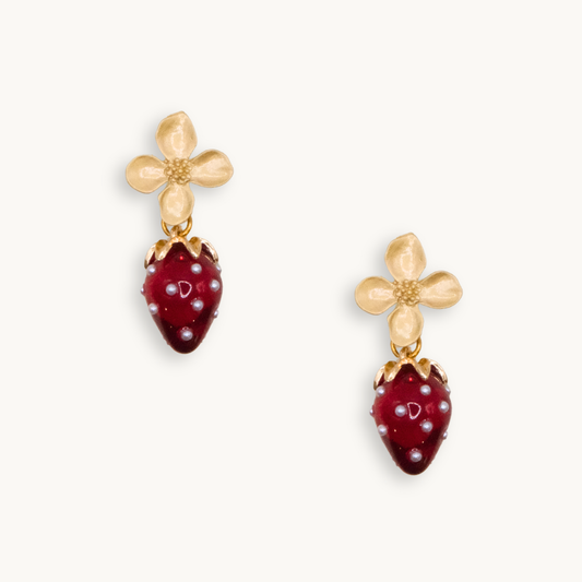 Gold flower earrings with red strawberry charms featuring tiny pearl-like dots. The design is whimsical, delicate, and playful.