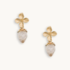 Gold flower earrings with white strawberry charms featuring tiny pearl-like dots. The design is whimsical, delicate, and playful.