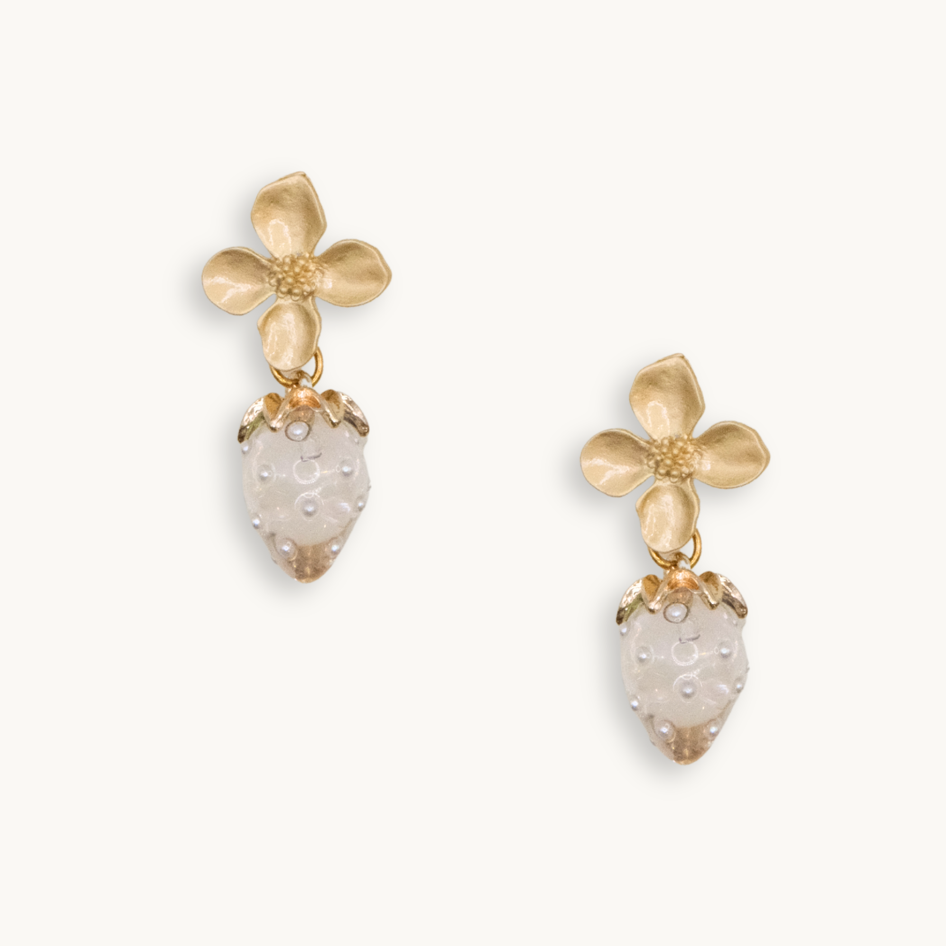 Gold flower earrings with white strawberry charms featuring tiny pearl-like dots. The design is whimsical, delicate, and playful.