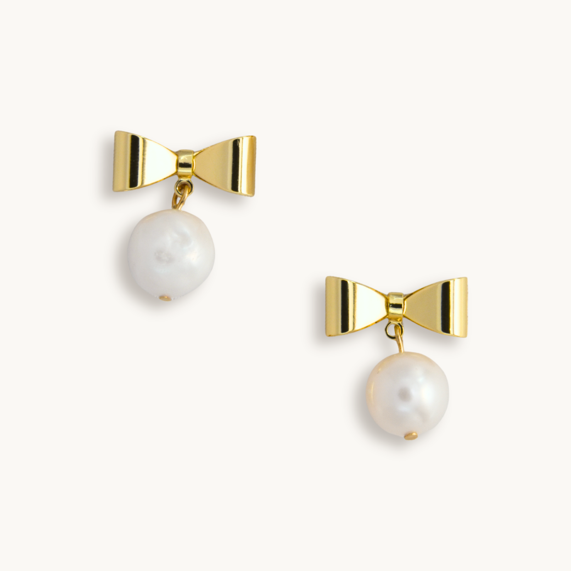 Gold bow earrings with dangling circular pearls on a white background