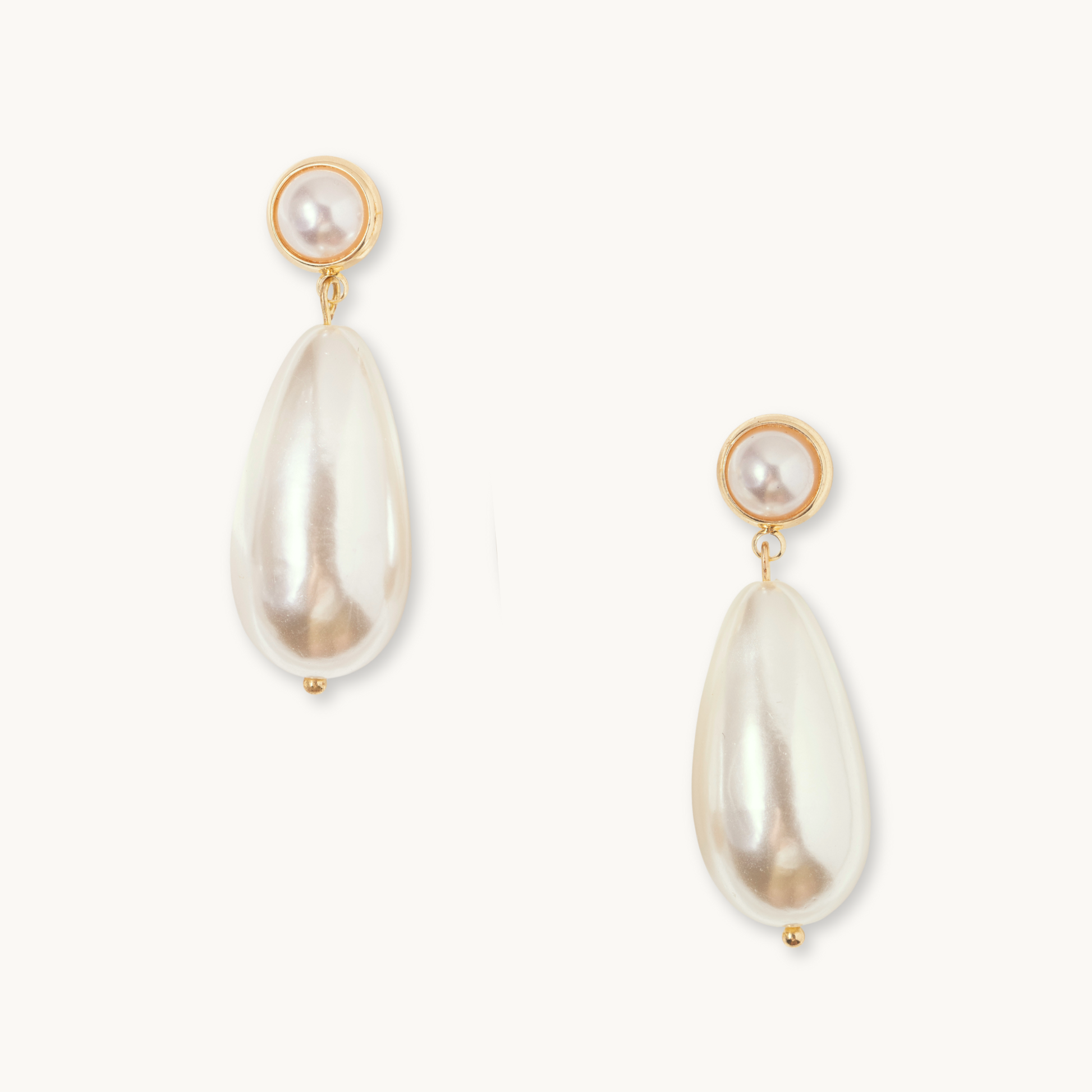 Elegant gold earrings featuring round pearl studs and elongated teardrop-shaped pearls, set against a plain white background, exuding a sophisticated tone.