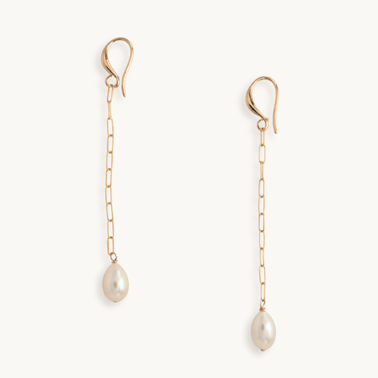 Gold chain earrings with elegant hooks and dangling pearls on a white background, conveying a sense of sophistication and minimalistic elegance.