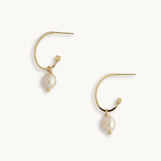 Gold hoop earrings with dangling white pearls. The minimalist design and delicate pearls create an elegant and sophisticated look.