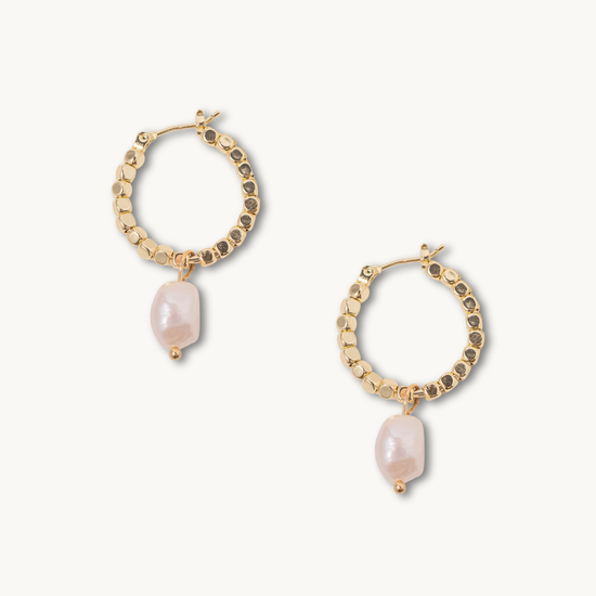 Gold hoop earrings with textured beads and dangling irregular pearls on a white background, conveying elegance and sophistication.