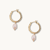 Gold hoop earrings with textured beads and dangling irregular pearls on a white background, conveying elegance and sophistication.