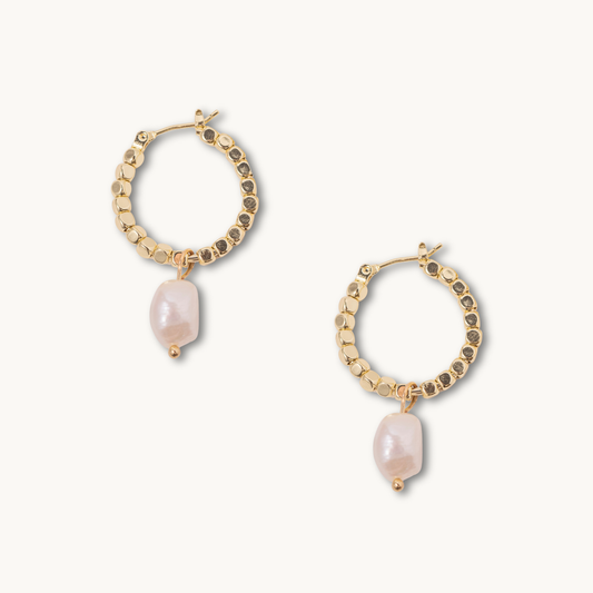 Gold hoop earrings with textured beads and dangling irregular pearls on a white background, conveying elegance and sophistication.