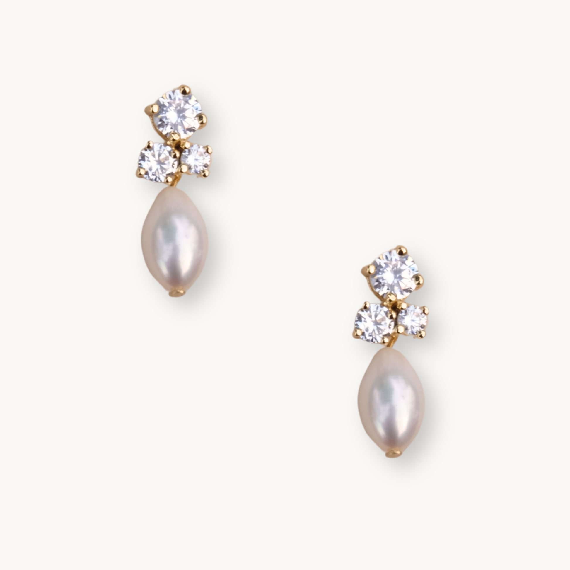 Gold stud earrings feature three sparkling diamonds and a dangling teardrop pearl. The elegant design conveys luxury and sophistication.