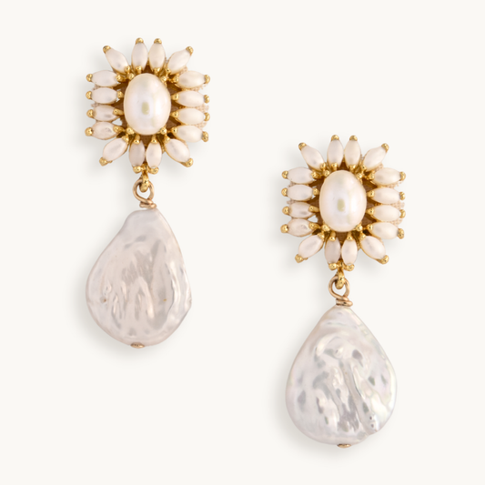 Elegant gold earrings feature a central pearl surrounded by smaller marquise pearls, with large, lustrous baroque pearl drops, exuding sophistication.