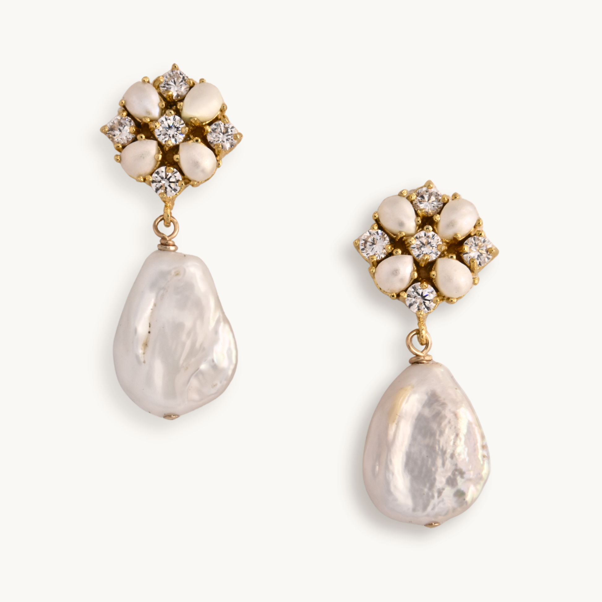 Elegant earrings featuring a cluster of sparkling diamonds and pearls set in a floral pattern, with a teardrop-shaped pearl dangling below in gold settings.
