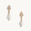 Elegant pearl drop earrings with gold art deco settings, against a plain white background. The design is classic and sophisticated.
