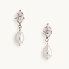 Elegant pearl drop earrings with silver art deco settings, against a plain white background. The design is classic and sophisticated.