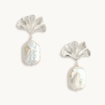 Silver earrings featuring ginkgo leaf designs with dangling irregular-shaped baroque pearls. The tone is elegant and sophisticated.