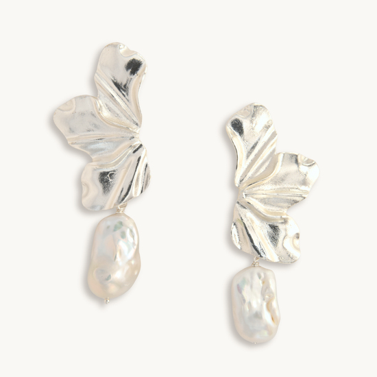 Silver earrings with leaf-like designs on a white background