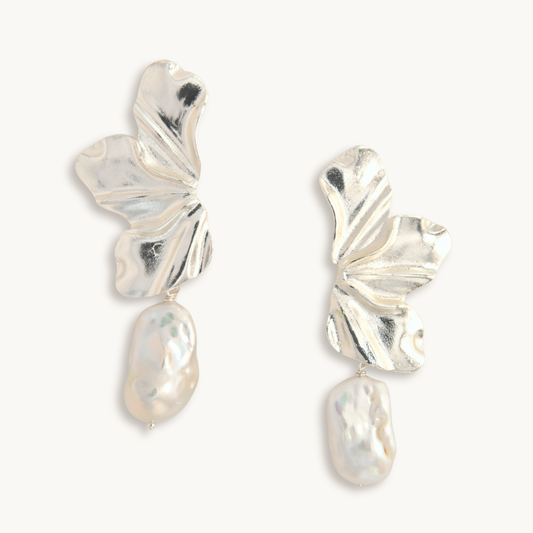 Silver earrings with leaf-like designs on a white background