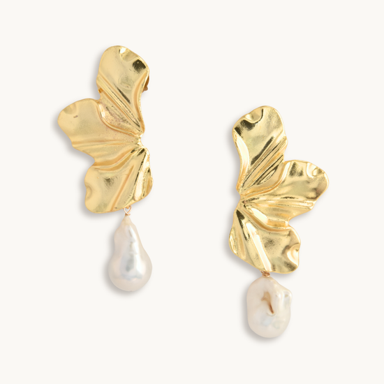Gold leaf earrings with pearl drops on a white background